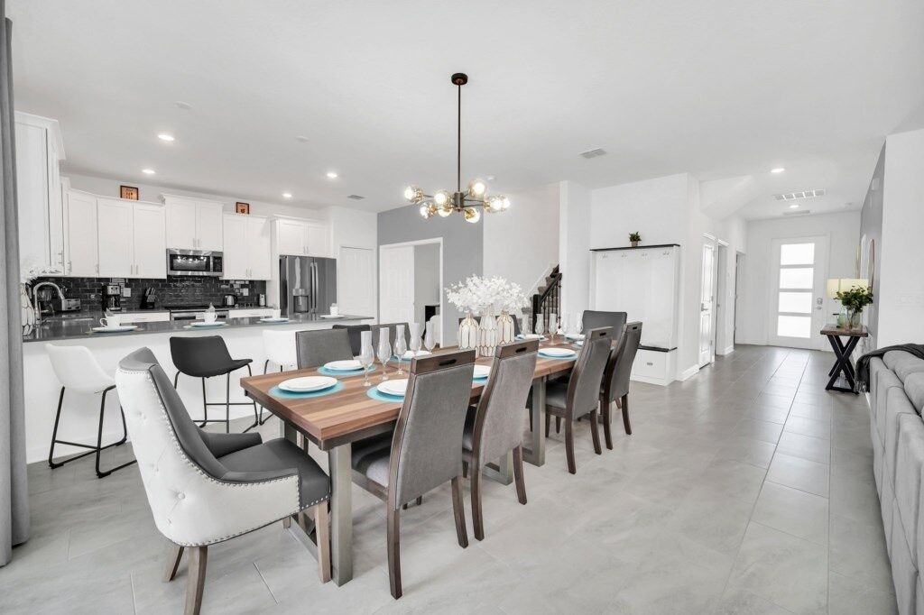 A modern kitchen with white cabinets, a central island, and a dining area with a wooden table and chairs.