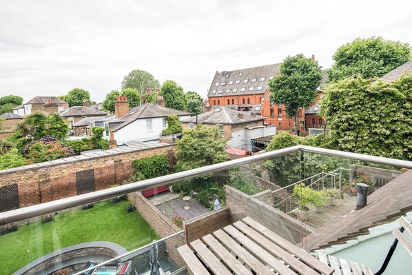 A residential area with a view of a brick building, a wooden deck, and a garden.