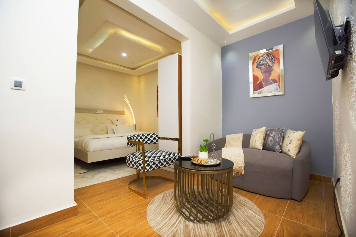 A modern living room with a sofa, a round coffee table, and a patterned armchair.