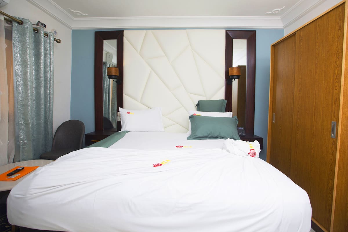 A hotel room with a bed, a desk, a chair, and a wardrobe.