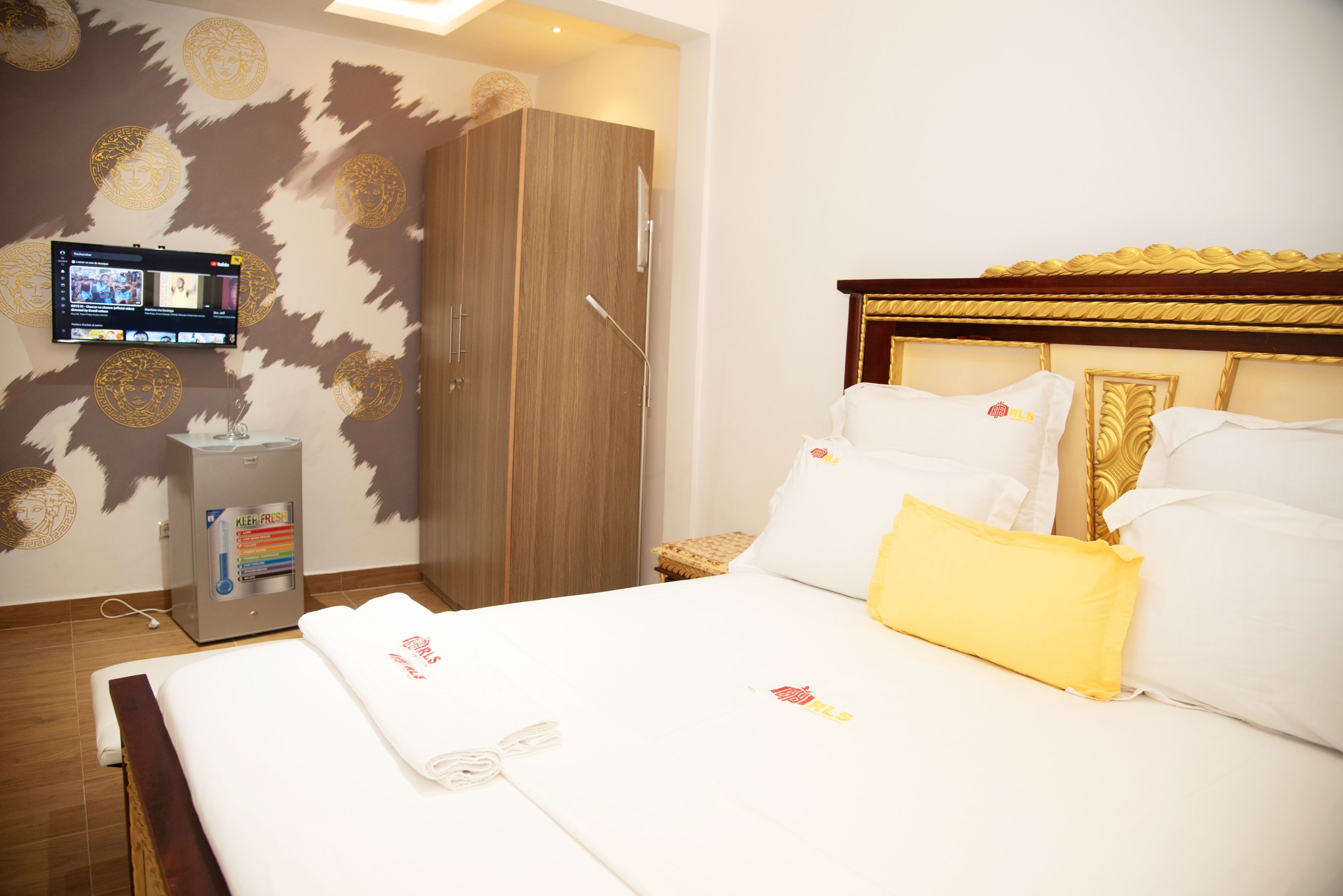 A hotel room with a bed, a wardrobe, a television, and a minibar.