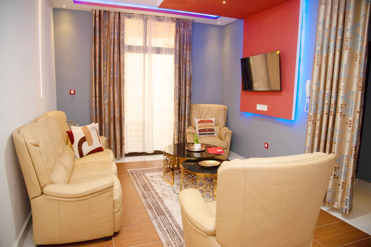 A living room with two beige sofas, a coffee table, and a TV mounted on the wall.