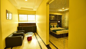 A hotel room with a seating area, a bed, and a window. - ANANYA COMFORTSS-OPP RAHEJA RESIDENCY  (Bengaluru)