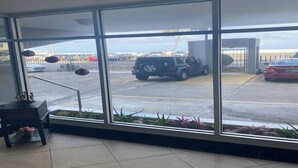Blick aus einem Gebäude durch große Fenster auf einen Parkplatz mit mehreren Autos.