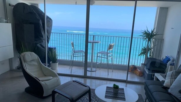 Ein Balkon mit Blick auf den Ozean, eine Couch, ein Sessel und ein kleiner Tisch mit einer Pflanze.
