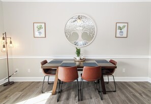 Enjoy meals with family and friends at this dining area, featuring a table for four, comfortable chairs, and beautiful artwork.