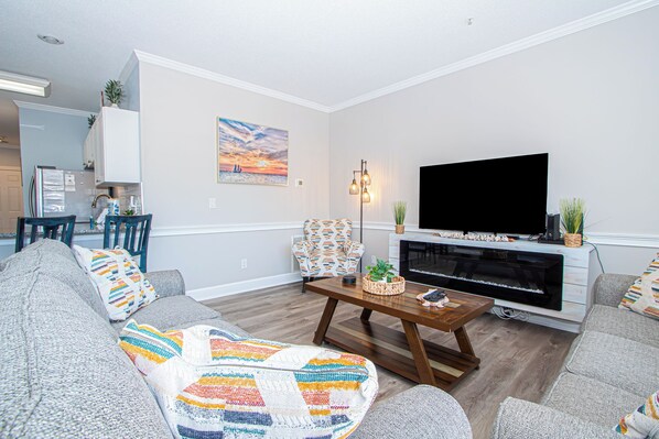 Relax in this stylish living room with a large flat-screen TV, comfortable sofa, and wooden coffee table.