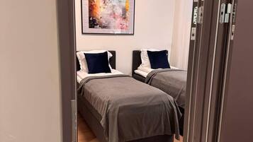 Une chambre avec deux lits, un plancher en bois et un tableau abstrait encadré accroché au mur.