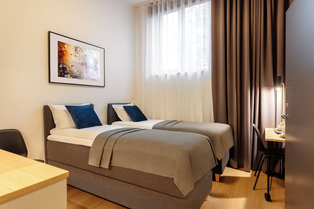 Une chambre d’hôtel avec deux lits, un bureau et une chaise.