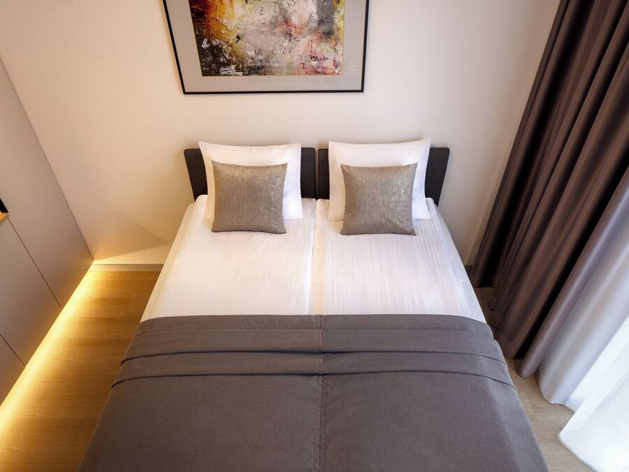 A double bed with two pillows, a headboard, and a framed abstract painting above.