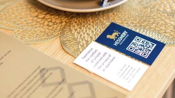 A cup and saucer on a textured table with a QR code and a business card.