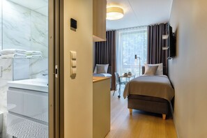 Relax in a serene space with a neatly made bed, bedside table, and window with natural light.