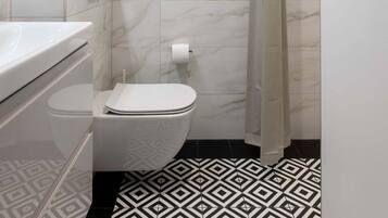 Een moderne badkamer met een wit toilet, een wastafel met spiegel en een douchegedeelte.