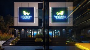 Een modern gebouw met twee verlichte borden waarop 'HESSNERY RESIDENTSIDY' staat.