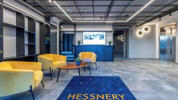 A modern lobby with a reception desk, seating area, and elevators.
