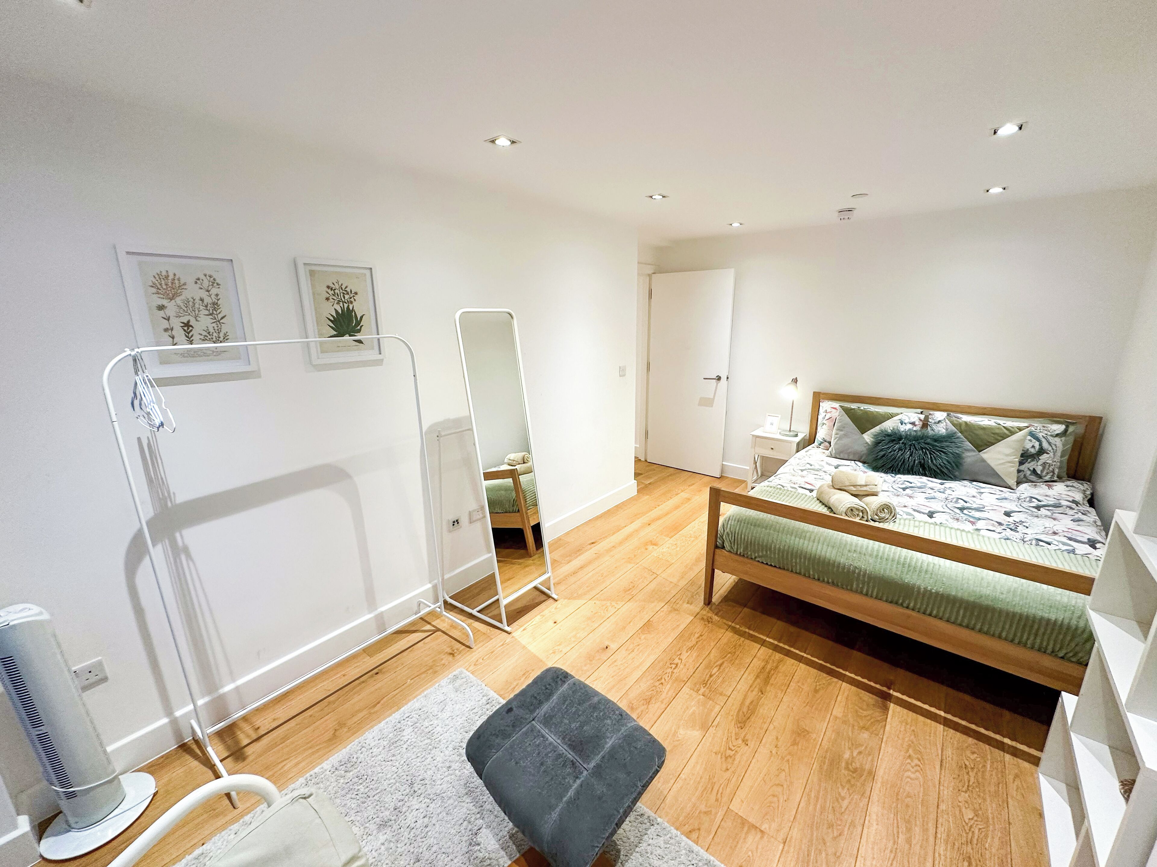 A bedroom with a bed, bedside table, and a mirror.