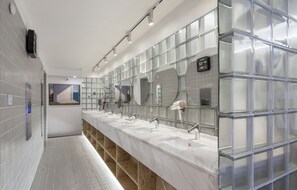 Een moderne badkamer met een lange wastafel, meerdere wasbakken en grote spiegels.