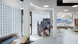 A modern interior with a curved ceiling, pendant lighting, a seating area with a sofa and tables, and a large window with a view of the street. - Meow Hero Youth Hostel (Shanghai)