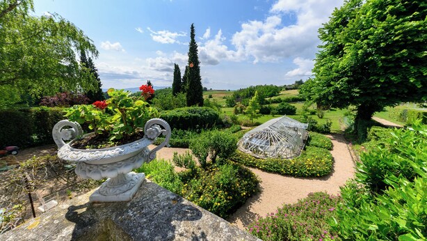 A garden with a decorative urn, a greenhouse, and neatly trimmed hedges. - Domaine de Montclair (Pommiers)