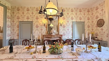 Comedor con candelabro, papel tapiz floral y una mesa dispuesta para una comida.