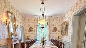 A dining room with a long table set for a meal, surrounded by chairs. - Domaine de Montclair (Pommiers)