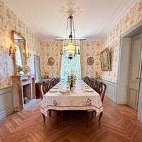 Un comedor con una larga mesa dispuesta para una comida, rodeada de sillas.