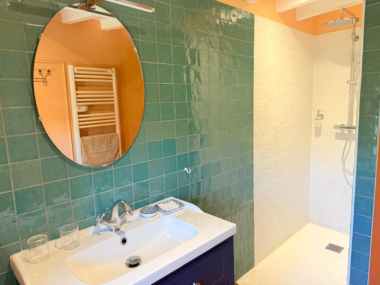 Un baño con lavamanos, espejo, toallero y ducha.