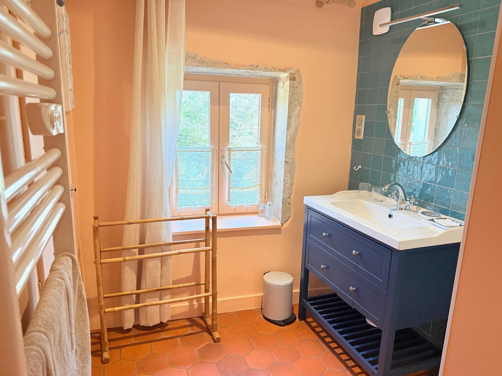 A bathroom with a window, a sink, a mirror, and a towel rack.
