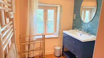 A bathroom with a window, a sink, a mirror, and a towel rack.