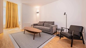 Un salon moderne comprenant un canapé, une table basse, un fauteuil et un lampadaire.