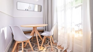 A modern room with a round wooden table and two white chairs, a mirror, and sheer curtains. - Sweett | Gran Via 204 (Barcelona)