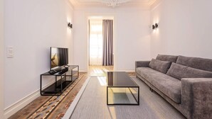 A modern living room with a grey sofa, a black coffee table, and a TV on a black stand. - Sweett | Gran Via 302 (Barcelona)