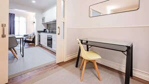 Moderni huone, jossa on lasinen työpöytä, tuoli, peili ja näkymä keittiötilaan.
