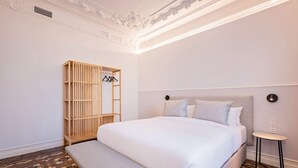 Siististi järjestetty hotellihuone, jossa on suuri sänky, puinen vaatekaappi ja pieni yöpöytä.