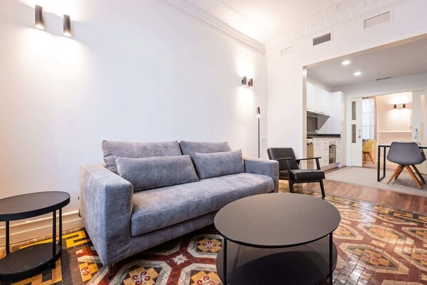 Un salon moderne avec un canapé gris, une table basse ronde et un sol à motifs.