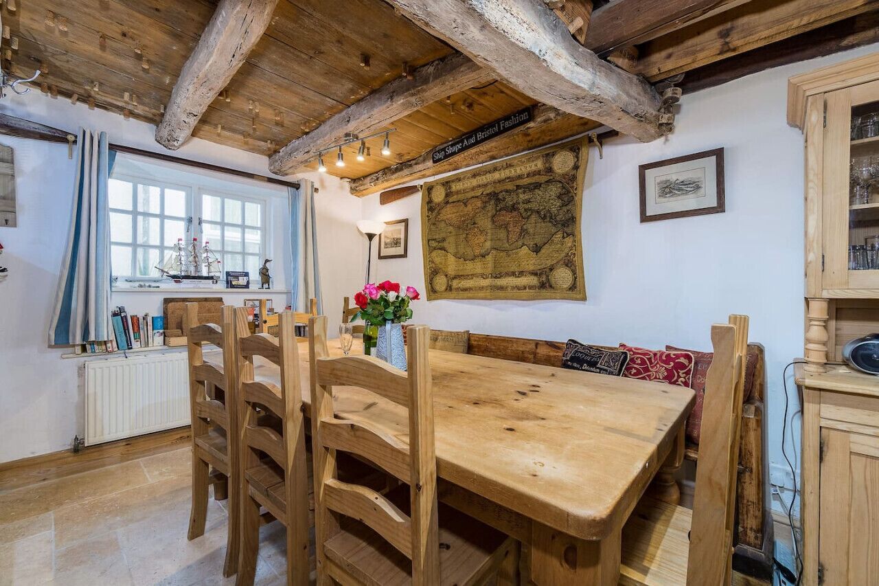 A rustic dining area with wooden furniture, a map on the wall, and a window with curtains.
