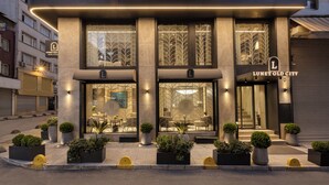 Un edificio moderno con un llamativo logo 'L', grandes ventanales y mesas al aire libre.