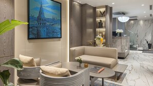Una sala de estar moderna con un sofá, sillones, una mesa de centro y un cuadro de un paisaje urbano.