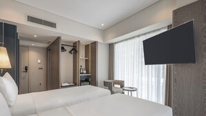 Una habitación de hotel con dos camas, un televisor, una mesita y un armario.