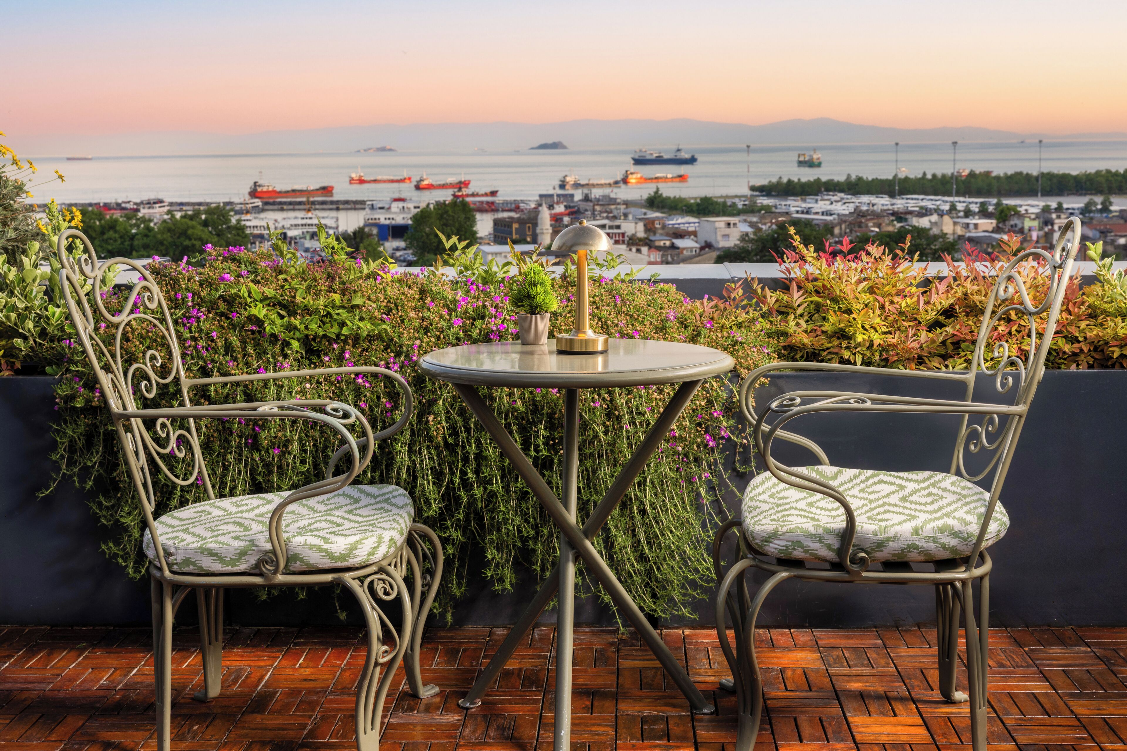 A balcony with two metal chairs, a small round table, and a potted plant.