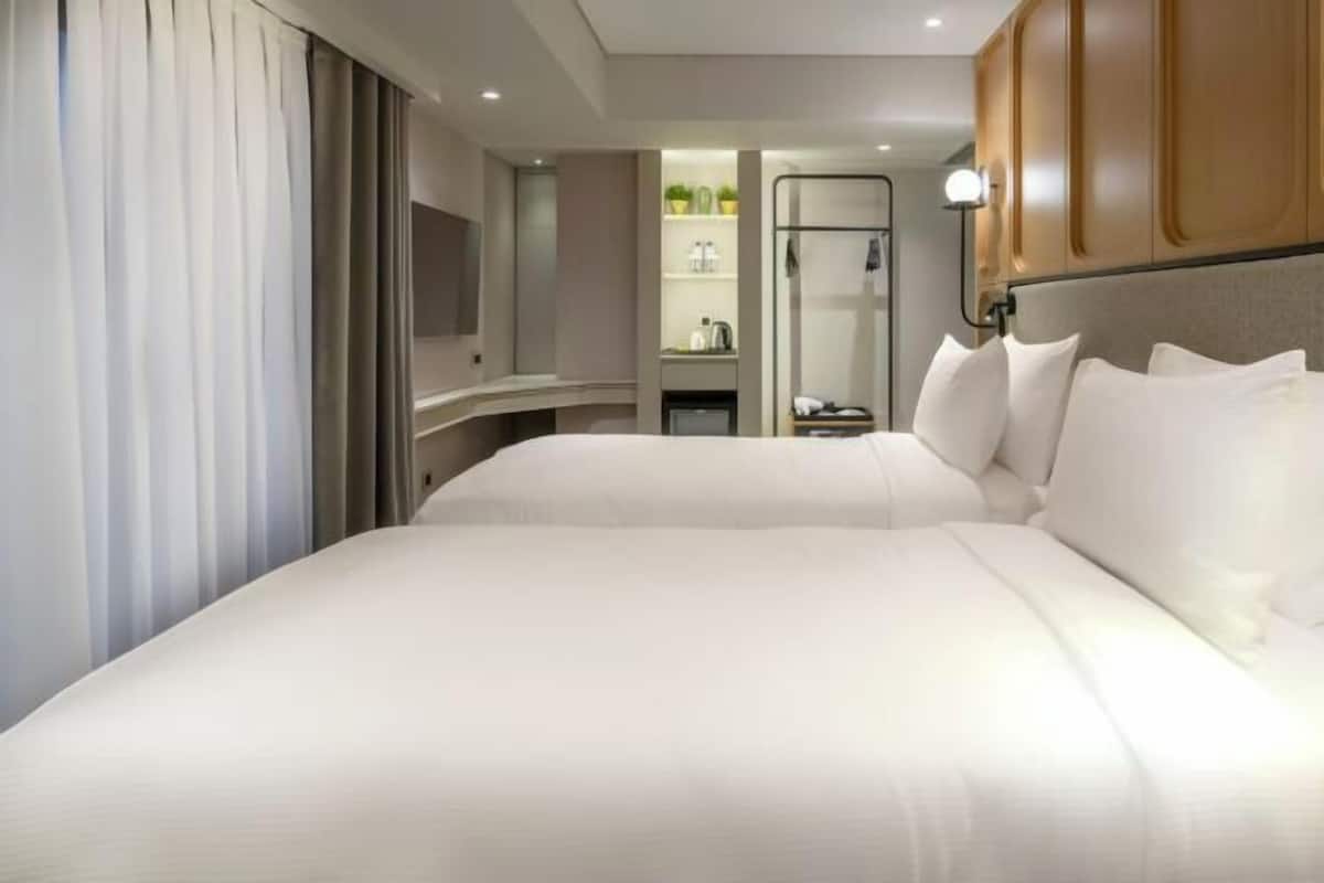Quarto de hotel com uma cama grande, uma mesinha de cabeceira, um espelho e um guarda-roupa.