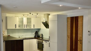 A modern kitchen with white cabinets, a built-in oven, and a coffee maker on the countertop. - Apartment in Fulpmes Near Stubai Glacier (Fulpmes)