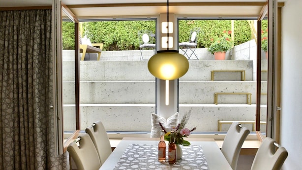 A dining area with a table set for four, a vase with flowers, and a pendant light. - Apartment in Fulpmes Near Stubai Glacier (Fulpmes)