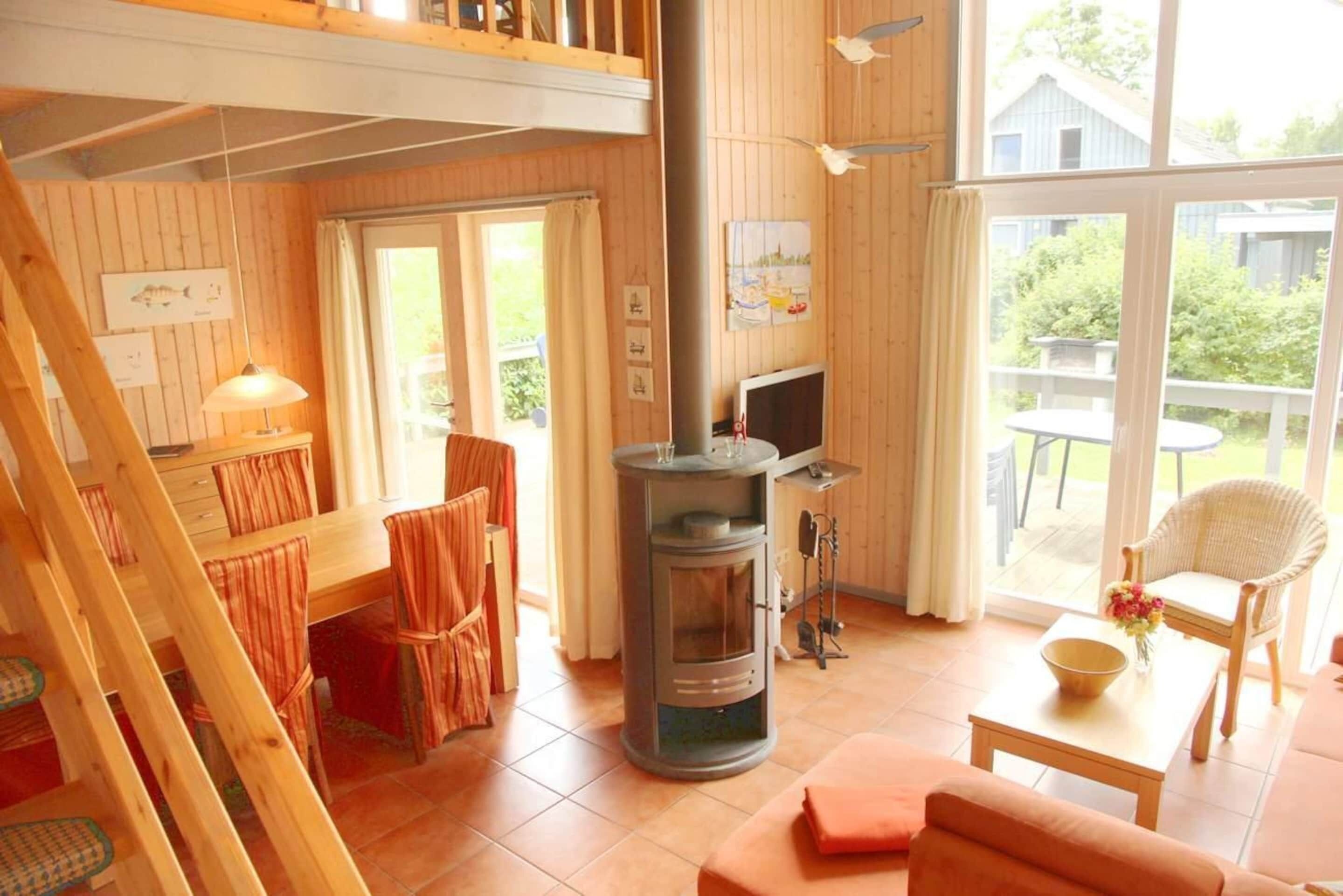 Un intérieur de chalet chaleureux avec un coin repas, un canapé, un téléviseur et un poêle à bois.