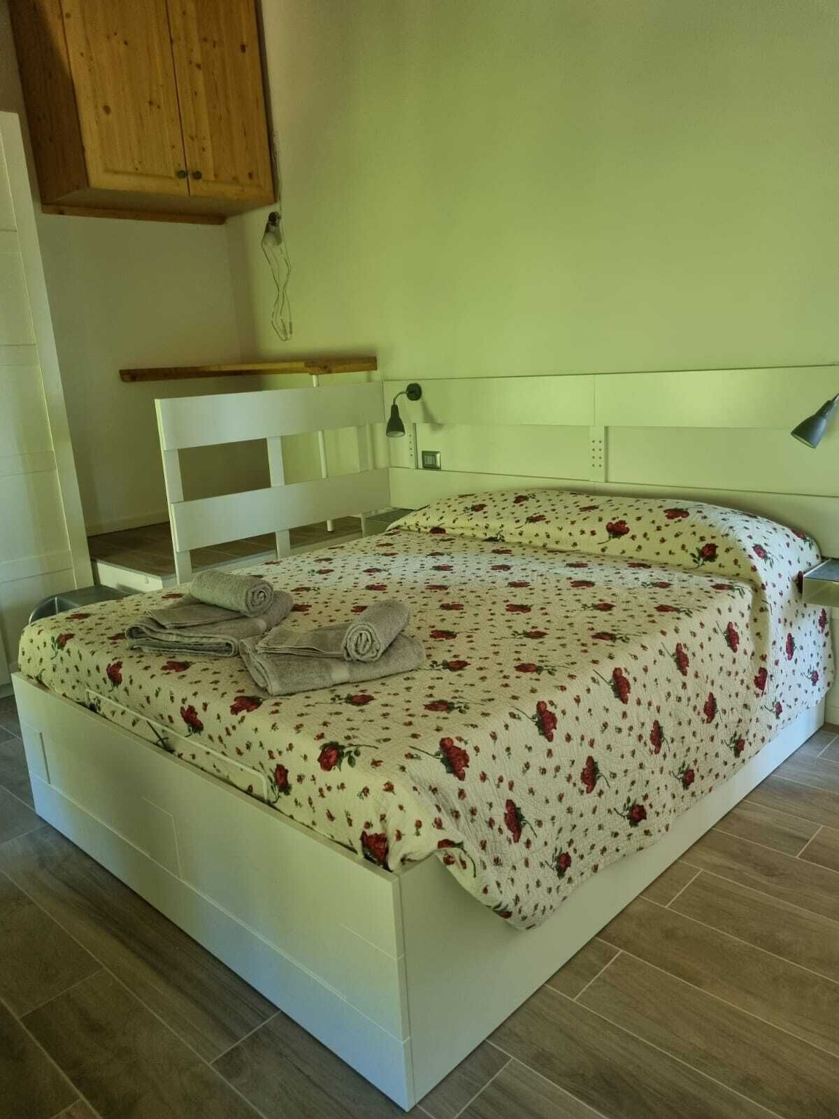 A bed with a floral bedspread, a wooden headboard, and a bedside lamp.