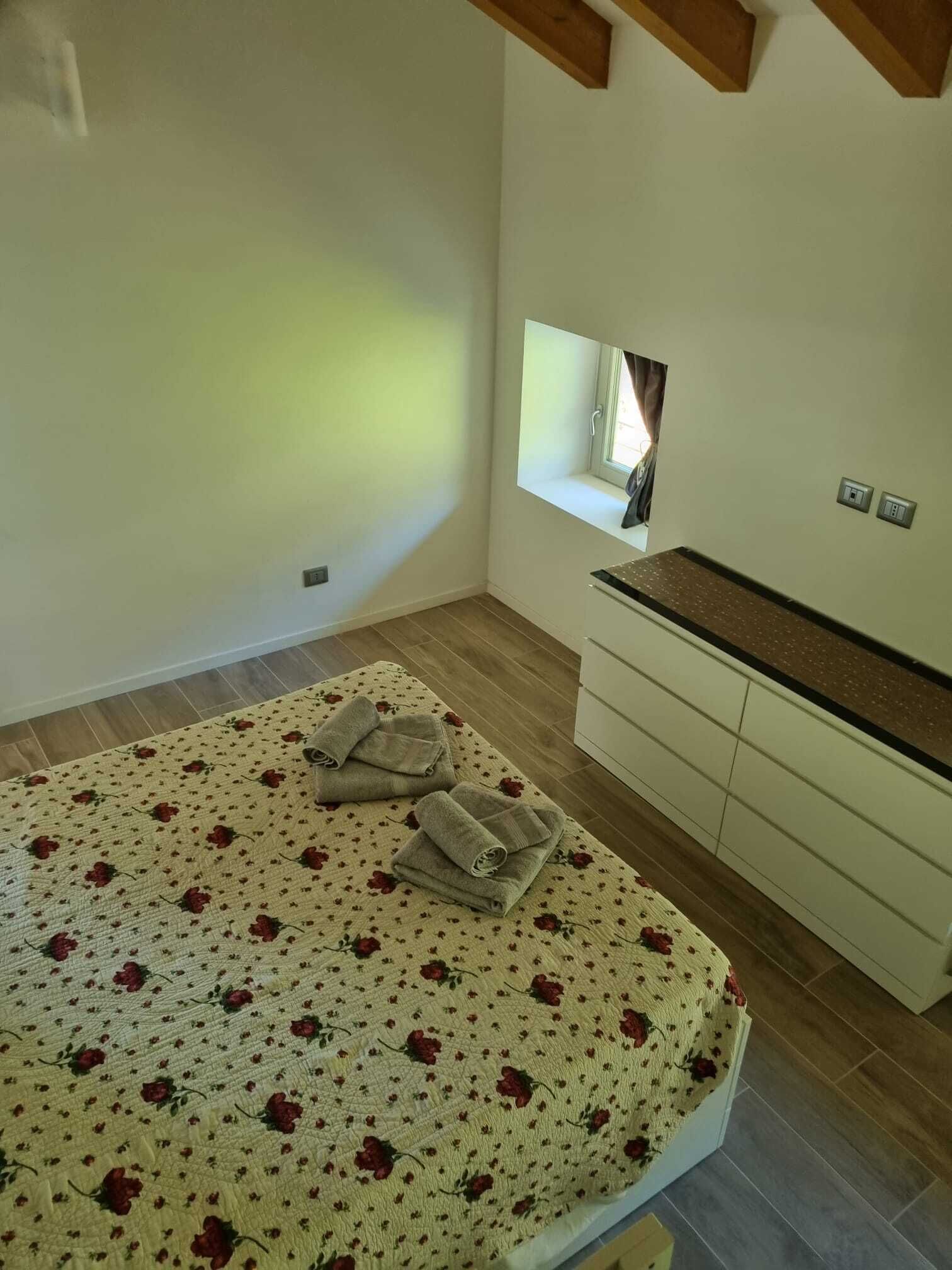 A bedroom with a bed, a window, a built-in bench, and a small window seat.