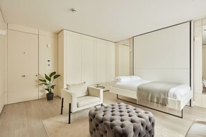 Quarto moderno com cama, poltrona, espelho grande e armários embutidos.