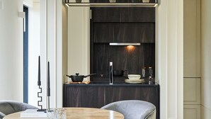 A modern kitchen with dark wood cabinets, a stainless steel range hood, and a round wooden table with two chairs. - Loftus Road (London)
