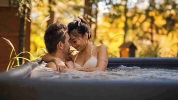 A couple in a hot tub surrounded by trees.