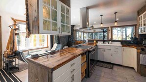 Una cocina moderna con una isla grande, armarios blancos y salpicadero de piedra.